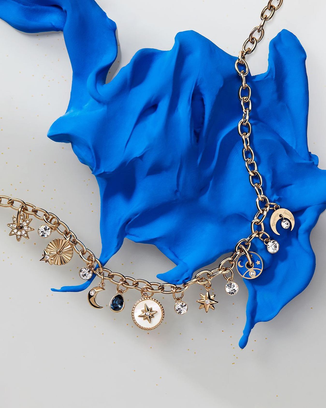 stainless steel necklace with star-themed pendants, mother-of-pearl, blue enamel, clear and montana color crystals.